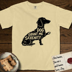 Serenity Dachshund T-Shirt flat lay in Butter, featuring Distressed black screen print silhouette of a Dachshund sitting in profile with one paw raised, a long low body and long hanging ears, the words DOG GRANT ME SERENITY showing through her body in the shirt color.
