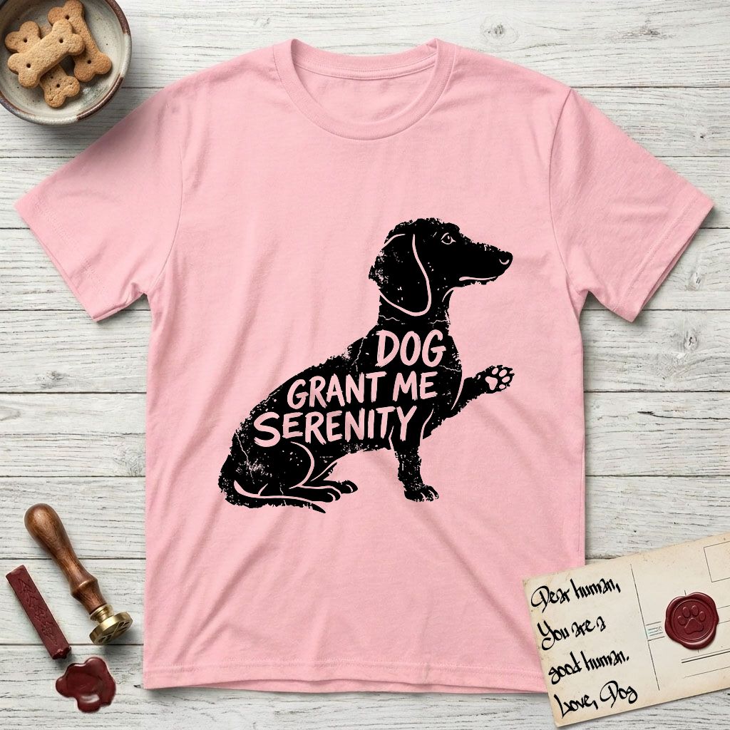 Serenity Dachshund T-Shirt flat lay in Light Pink, featuring Distressed black screen print silhouette of a Dachshund sitting in profile with one paw raised, a long low body and long hanging ears, the words DOG GRANT ME SERENITY showing through her body in the shirt color.