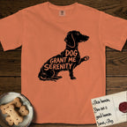Serenity Dachshund T-Shirt flat lay in Melon, featuring Distressed black screen print silhouette of a Dachshund sitting in profile with one paw raised, a long low body and long hanging ears, the words DOG GRANT ME SERENITY showing through her body in the shirt color.