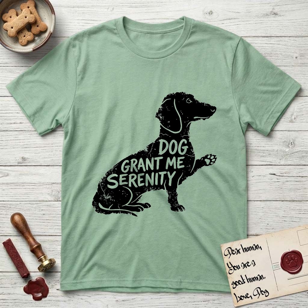 Serenity Dachshund T-Shirt flat lay in Mint Green, featuring Distressed black screen print silhouette of a Dachshund sitting in profile with one paw raised, a long low body and long hanging ears, the words DOG GRANT ME SERENITY showing through her body in the shirt color.