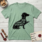 Serenity Dachshund T-Shirt flat lay in Mint Green, featuring Distressed black screen print silhouette of a Dachshund sitting in profile with one paw raised, a long low body and long hanging ears, the words DOG GRANT ME SERENITY showing through her body in the shirt color.