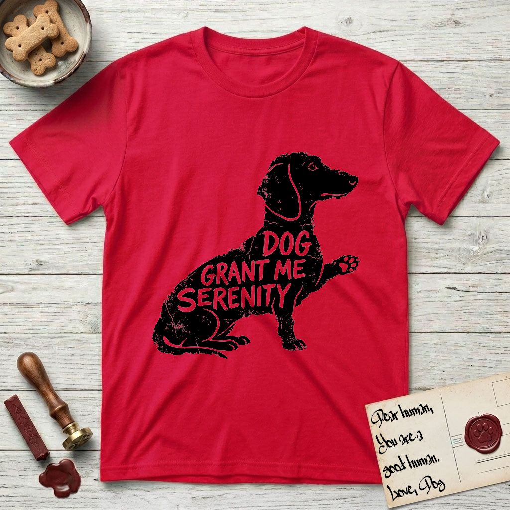 Serenity Dachshund T-Shirt flat lay in Red, featuring Distressed black screen print silhouette of a Dachshund sitting in profile with one paw raised, a long low body and long hanging ears, the words DOG GRANT ME SERENITY showing through her body in the shirt color.