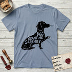 Serenity Dachshund T-Shirt flat lay in Stone Blue, featuring Distressed black screen print silhouette of a Dachshund sitting in profile with one paw raised, a long low body and long hanging ears, the words DOG GRANT ME SERENITY showing through her body in the shirt color.