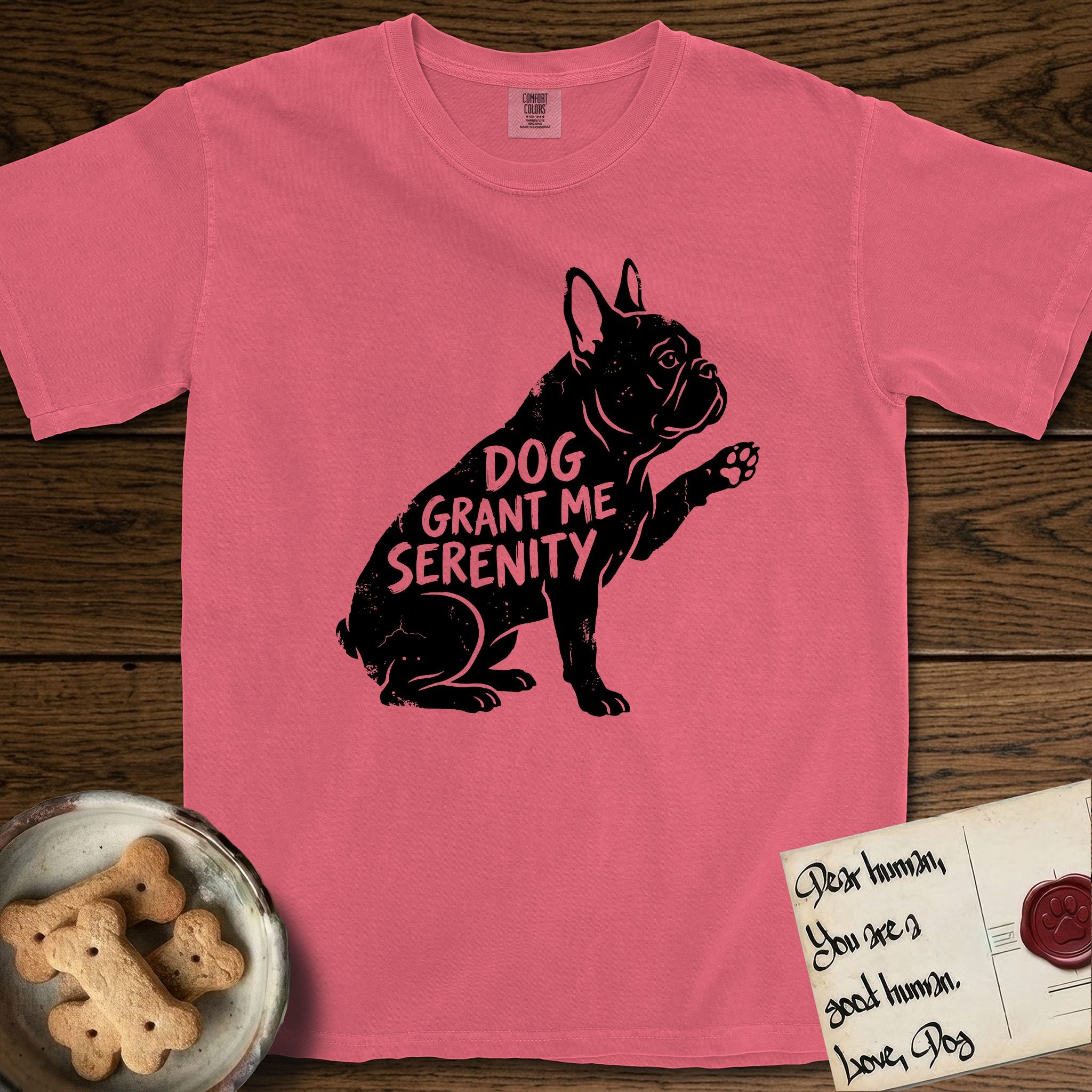 Serenity French Bulldog T-Shirt flat lay in Watermelon, featuring Distressed black screen print silhouette of a French Bulldog sitting in profile with one paw raised and large upright bat ears, the words DOG GRANT ME SERENITY showing through his body in the shirt color.