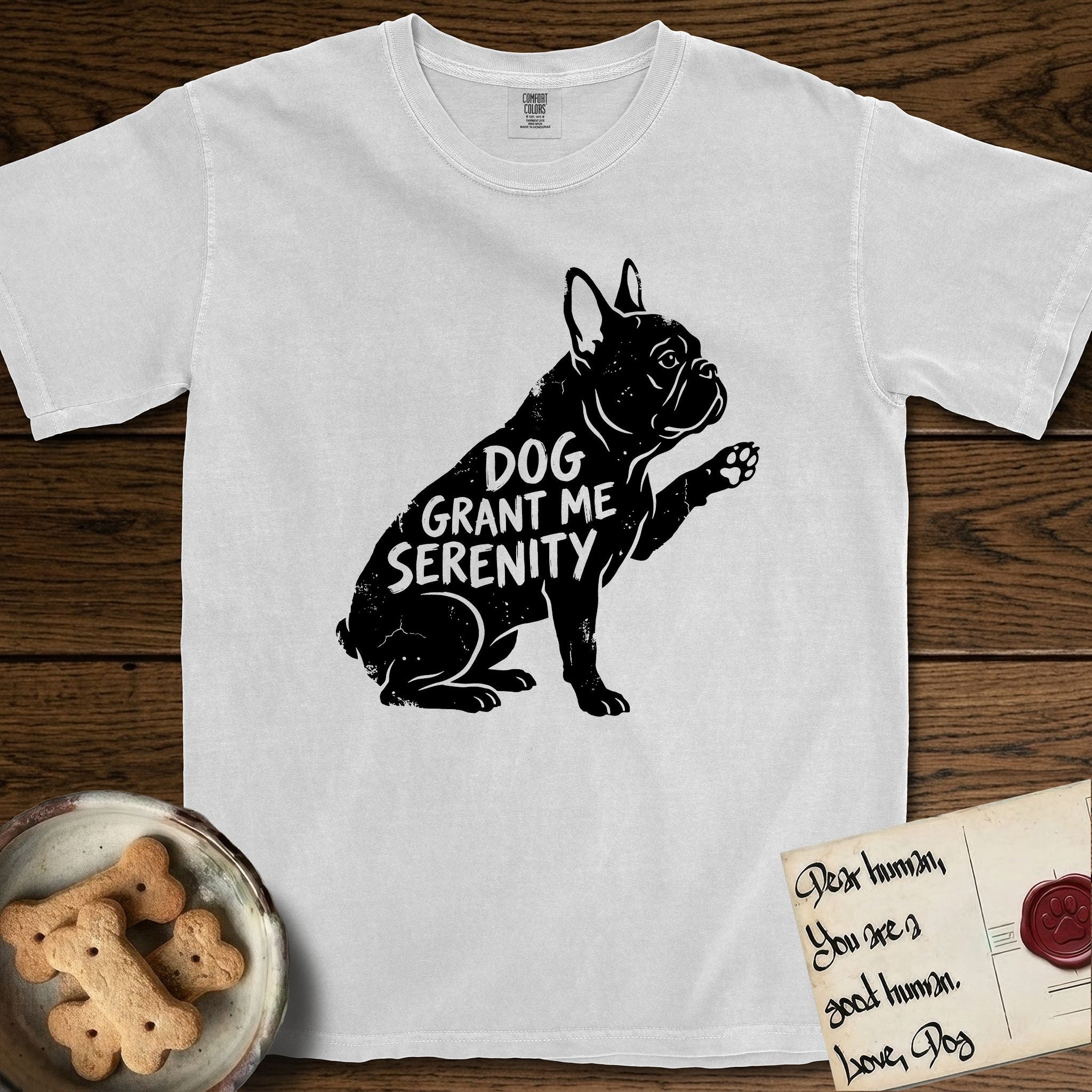 Serenity French Bulldog T-Shirt flat lay in White, featuring Distressed black screen print silhouette of a French Bulldog sitting in profile with one paw raised and large upright bat ears, the words DOG GRANT ME SERENITY showing through his body in the shirt color.
