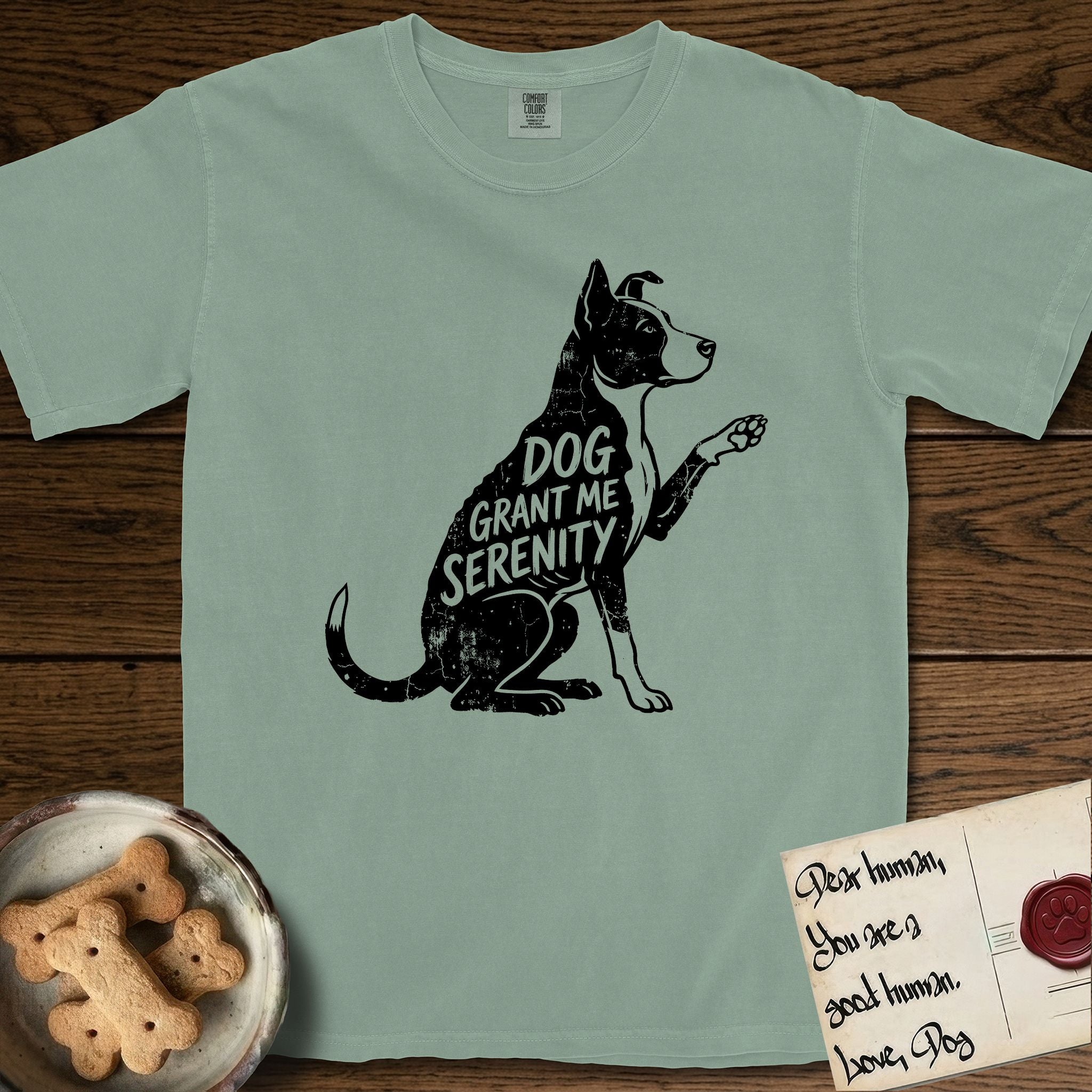 Serenity Lobo T-Shirt flat lay in Bay, featuring Distressed black screen print silhouette of a black and white Cattle Dog and Pitbull mix sitting in profile with one paw raised, a white blaze, white chest and white tail tip, the words DOG GRANT ME SERENITY showing through his body in the shirt color.