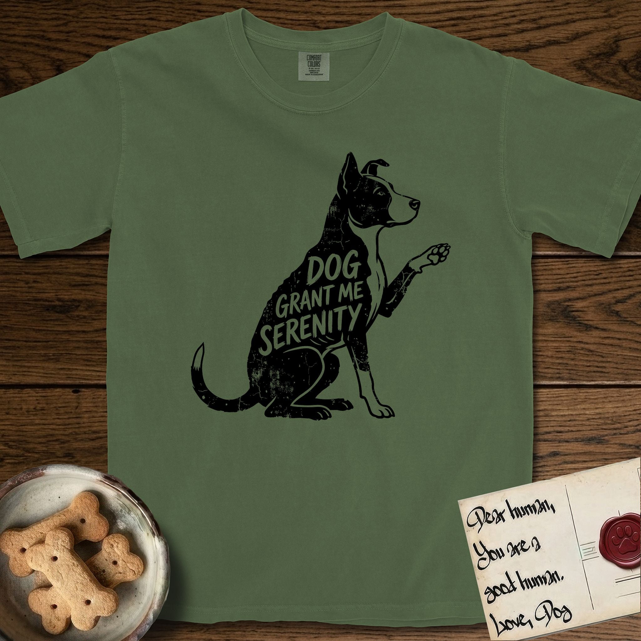 Serenity Lobo T-Shirt flat lay in Moss, featuring Distressed black screen print silhouette of a black and white Cattle Dog and Pitbull mix sitting in profile with one paw raised, a white blaze, white chest and white tail tip, the words DOG GRANT ME SERENITY showing through his body in the shirt color.