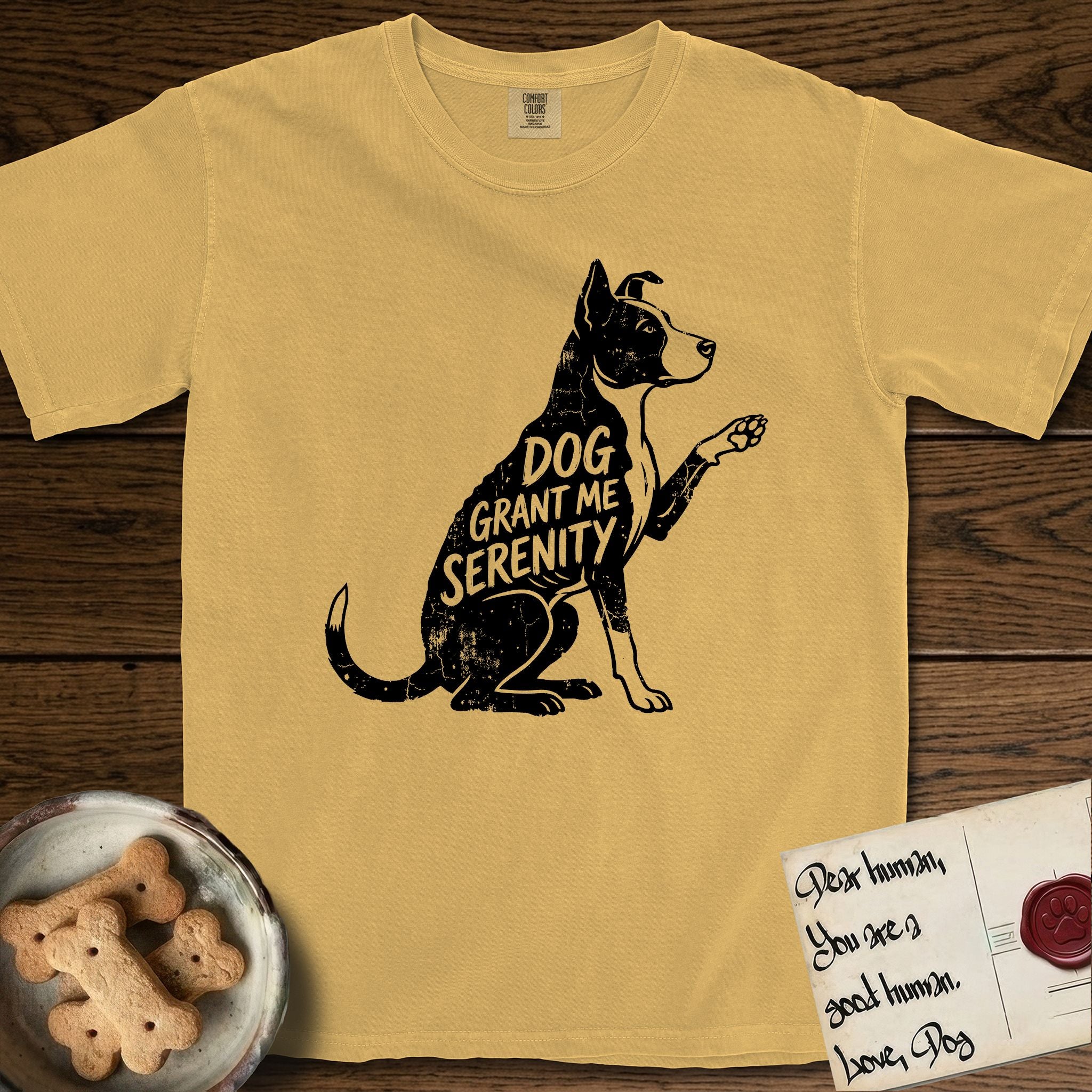 Serenity Lobo T-Shirt flat lay in Mustard, featuring Distressed black screen print silhouette of a black and white Cattle Dog and Pitbull mix sitting in profile with one paw raised, a white blaze, white chest and white tail tip, the words DOG GRANT ME SERENITY showing through his body in the shirt color.