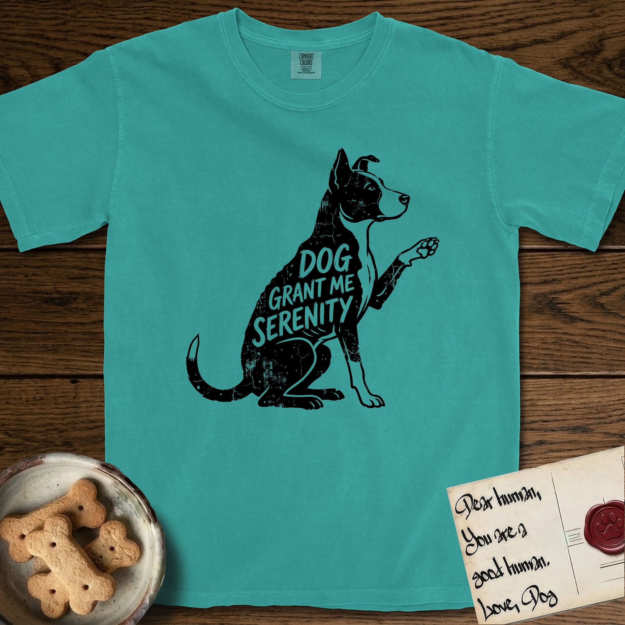 Serenity Lobo T-Shirt flat lay in Seafoam, featuring Distressed black screen print silhouette of a black and white Cattle Dog and Pitbull mix sitting in profile with one paw raised, a white blaze, white chest and white tail tip, the words DOG GRANT ME SERENITY showing through his body in the shirt color.