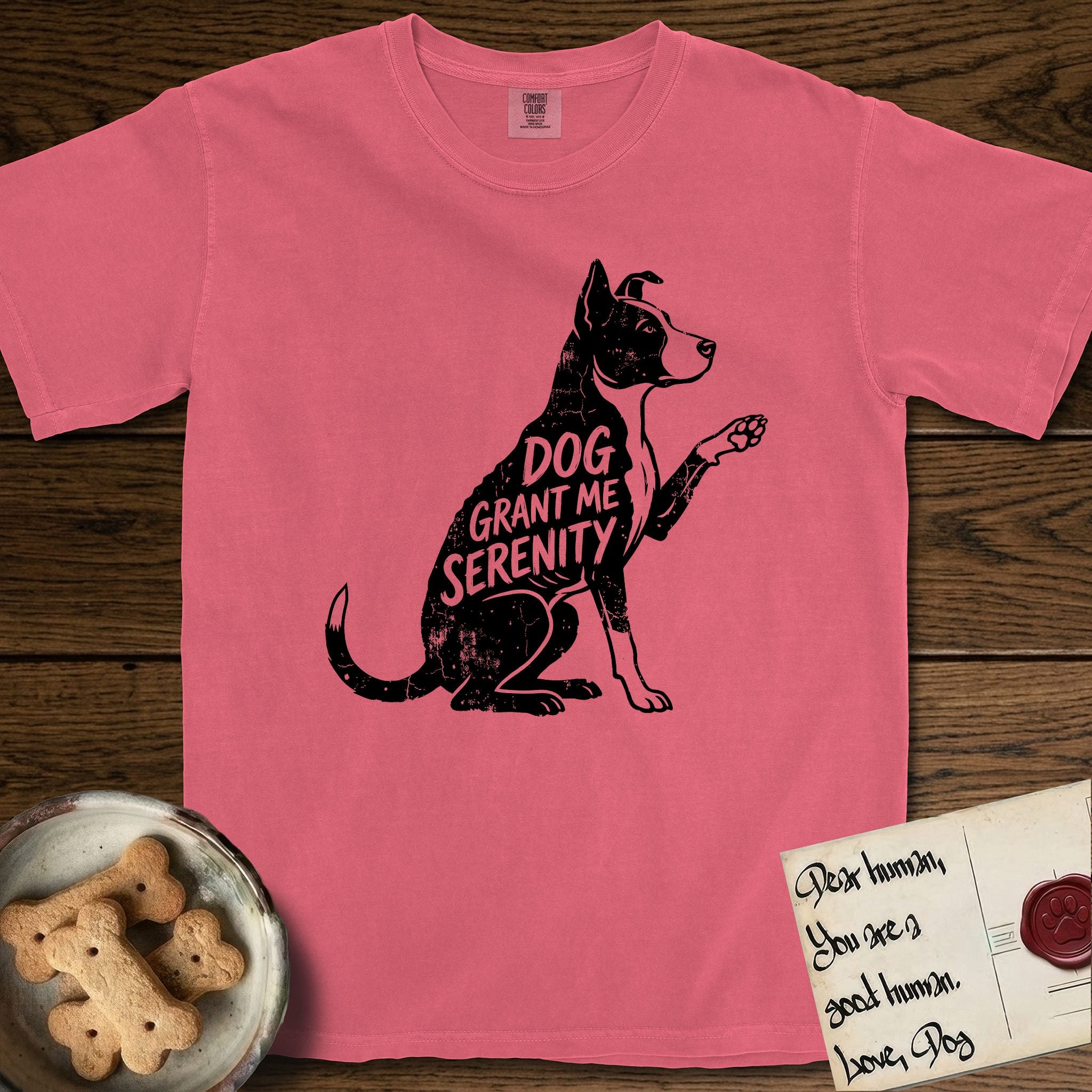 Serenity Lobo T-Shirt flat lay in Watermelon, featuring Distressed black screen print silhouette of a black and white Cattle Dog and Pitbull mix sitting in profile with one paw raised, a white blaze, white chest and white tail tip, the words DOG GRANT ME SERENITY showing through his body in the shirt color.