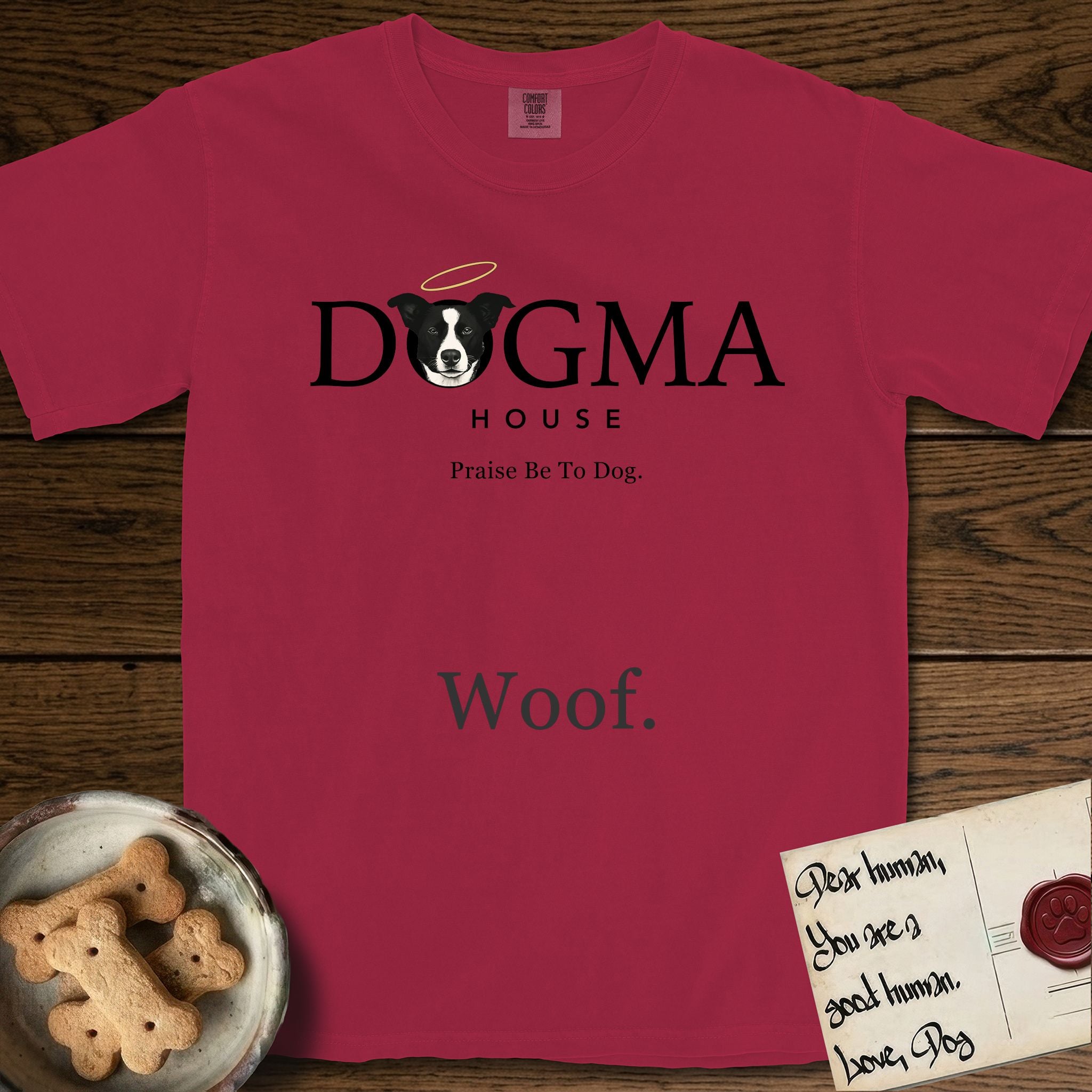 Dogma House Dark Logo T-Shirt flat lay in Chili, featuring the Dogma House wordmark in dark ink with Lobo the mascot forming the O, a halo above him, and HOUSE below.