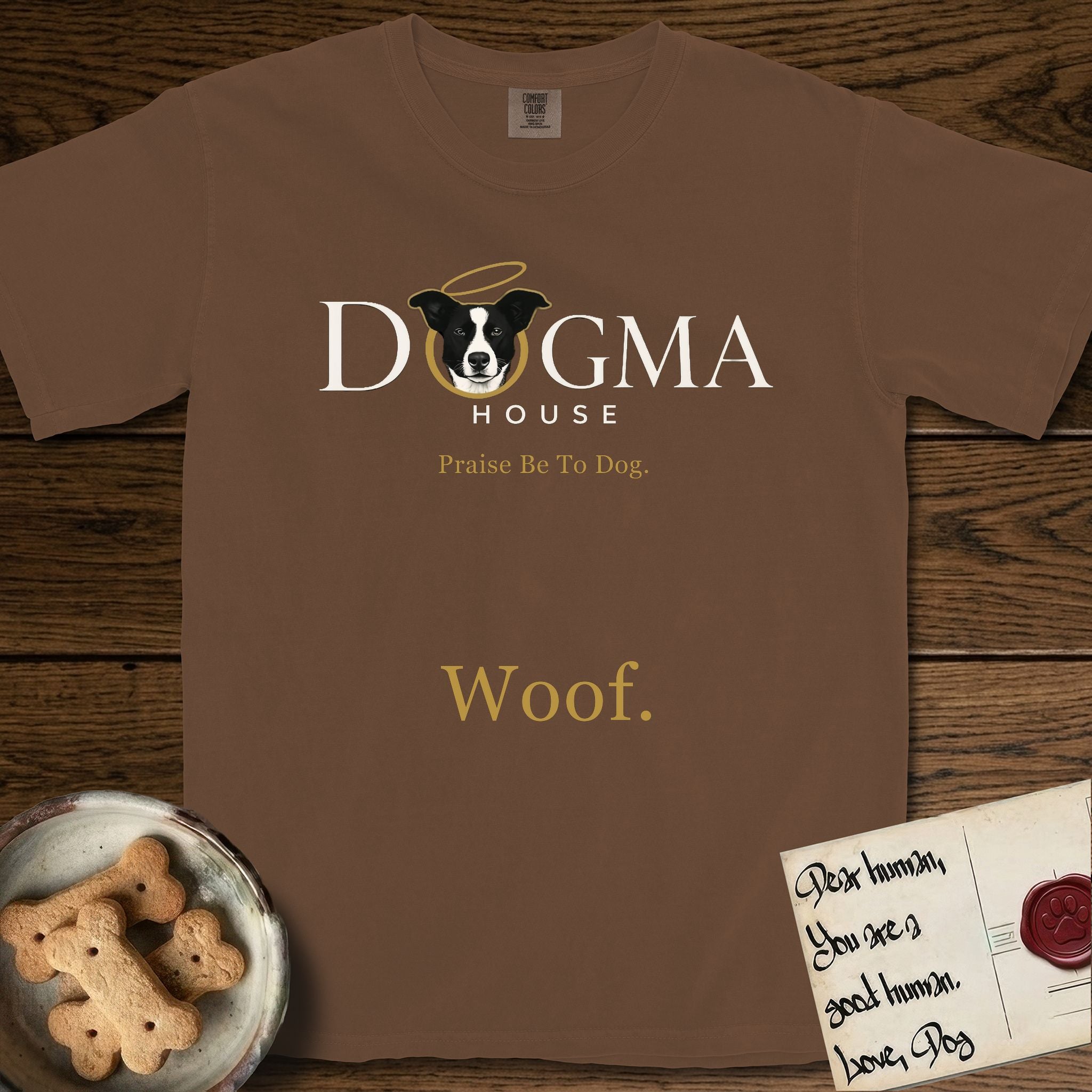 Dogma House Light Logo T-Shirt flat lay in Espresso, featuring the Dogma House wordmark in light ink with Lobo the mascot forming the O, a gold halo above him, and Woof below.