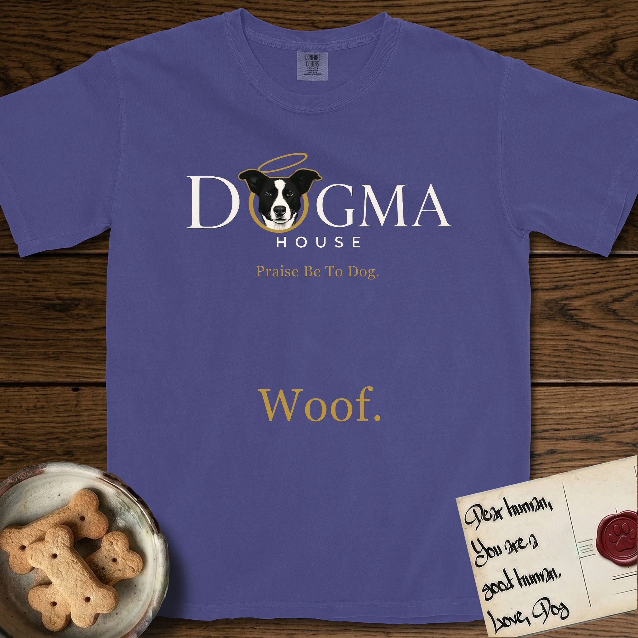Dogma House Light Logo T-Shirt flat lay in Grape, featuring the Dogma House wordmark in light ink with Lobo the mascot forming the O, a gold halo above him, and Woof below.