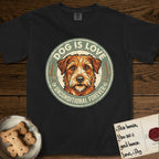 Dog is Love T-Shirt flat lay in Black, featuring a vintage distressed circular badge with a scruffy terrier on a sage-green ground, the words Dog Is Love and Unconditional Forever, and flanking paw prints.