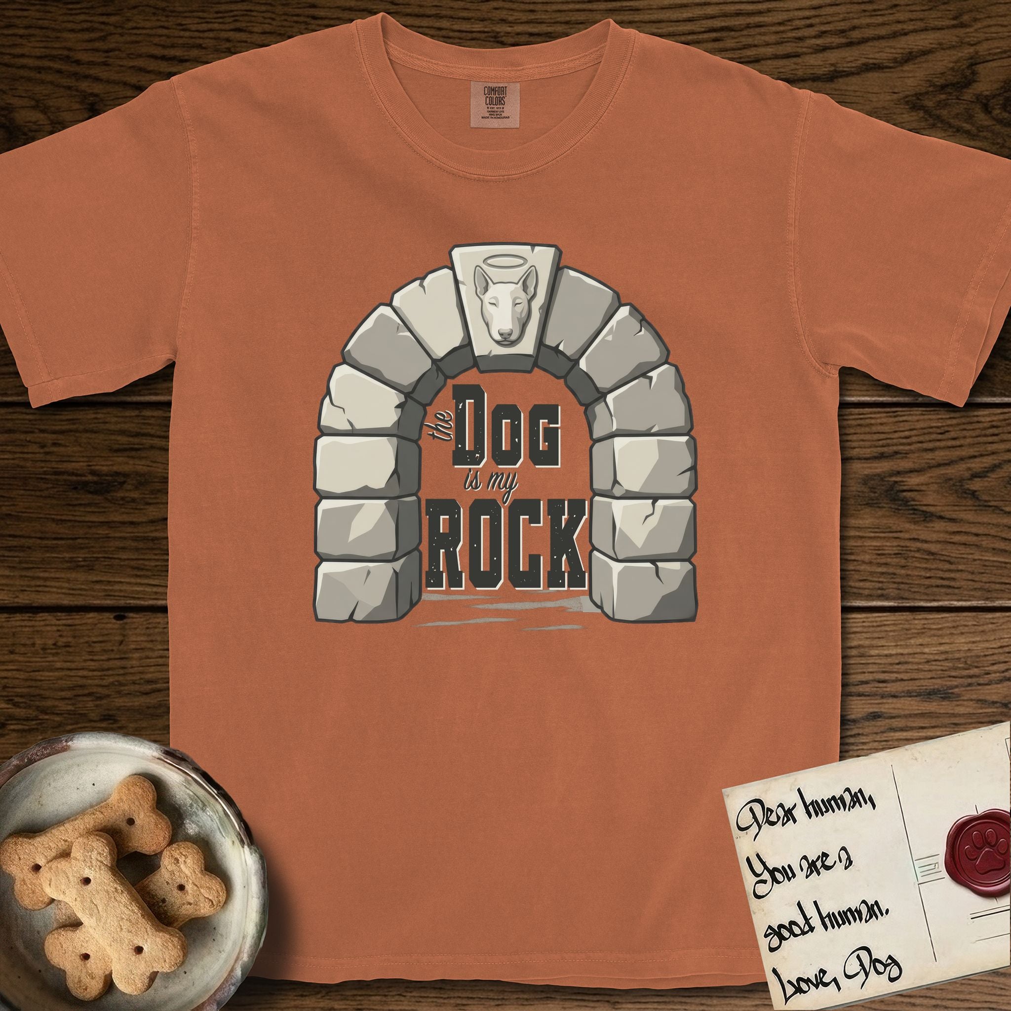 DIMR Bull Terrier T-Shirt flat lay in Yam, featuring carved gray stone arch with a Bull Terrier's face in shallow relief on the keystone and a halo above, with the words the Dog is my Rock.