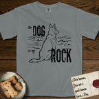 DIMR German Shepherd T-Shirt flat lay in Granite, featuring ink-line illustration of a German Shepherd seen from behind, sitting at the waterline and watching a stormy sea, with the words the Dog is my Rock.