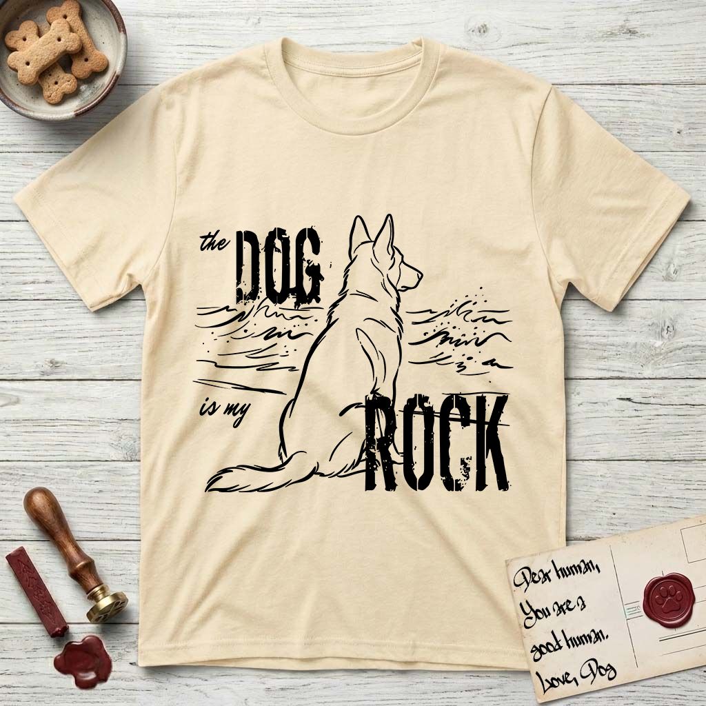DIMR German Shepherd T-Shirt flat lay in Natural, featuring ink-line illustration of a German Shepherd seen from behind, sitting at the waterline and watching a stormy sea, with the words the Dog is my Rock.