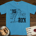 DIMR German Shepherd T-Shirt flat lay in Royal Caribe, featuring ink-line illustration of a German Shepherd seen from behind, sitting at the waterline and watching a stormy sea, with the words the Dog is my Rock.