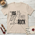 DIMR German Shepherd T-Shirt flat lay in Sand, featuring ink-line illustration of a German Shepherd seen from behind, sitting at the waterline and watching a stormy sea, with the words the Dog is my Rock.