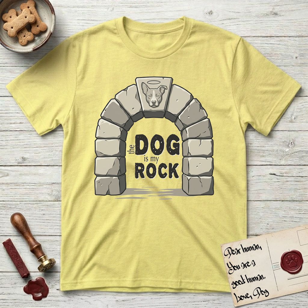DIMR Lobo T-Shirt flat lay in Cornsilk, featuring carved gray stone arch with Lobo's Cattle Dog face in shallow relief on the keystone and a halo above, with the words the Dog is my Rock.