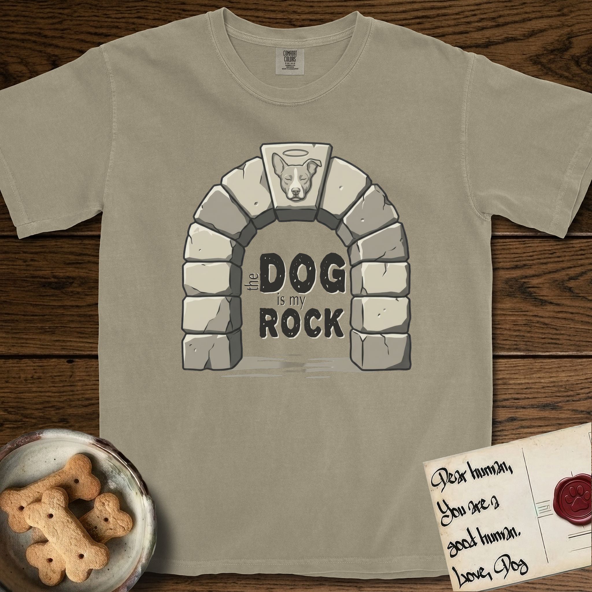 DIMR Lobo T-Shirt flat lay in Khaki, featuring carved gray stone arch with Lobo's Cattle Dog face in shallow relief on the keystone and a halo above, with the words the Dog is my Rock.