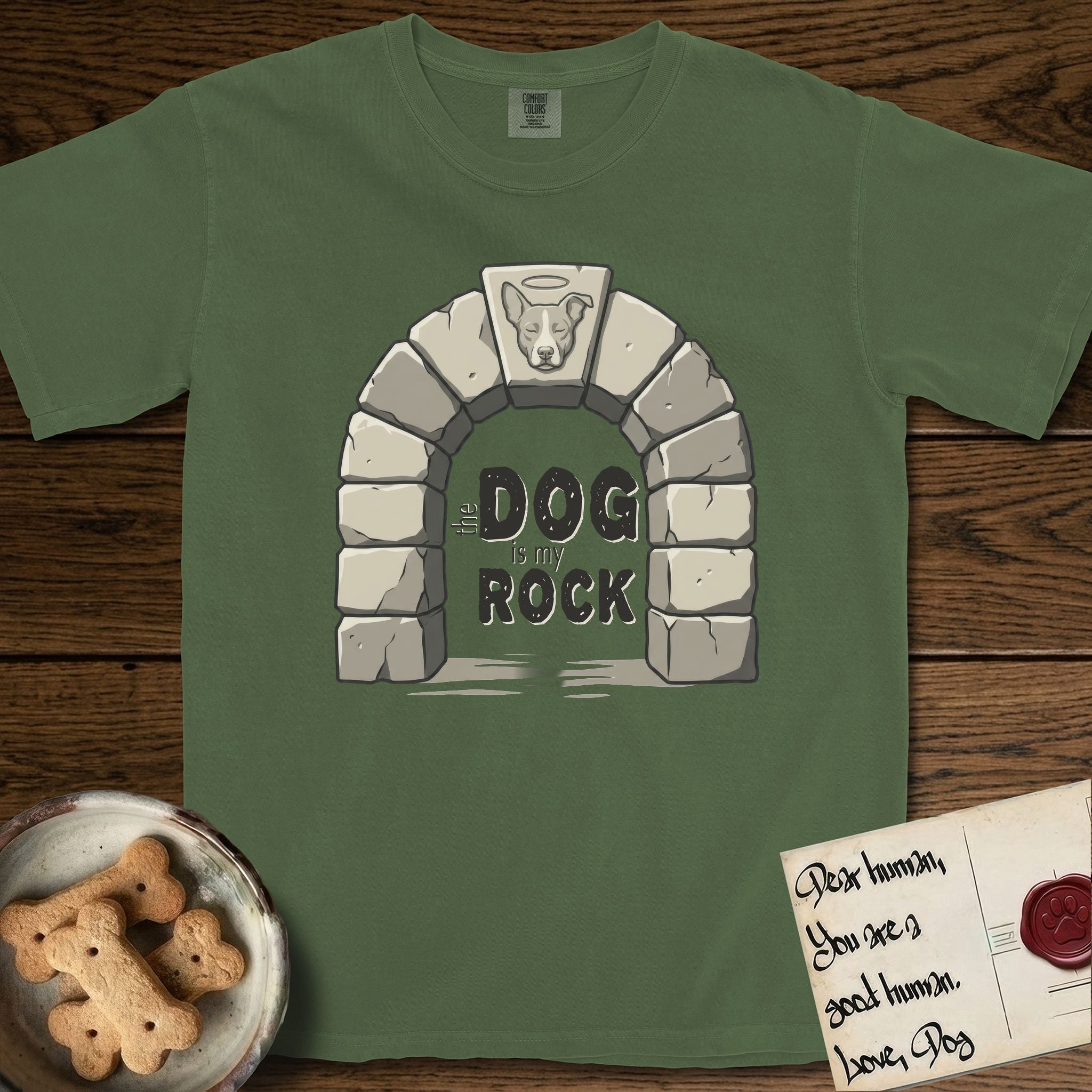 DIMR Lobo T-Shirt flat lay in Moss, featuring carved gray stone arch with Lobo's Cattle Dog face in shallow relief on the keystone and a halo above, with the words the Dog is my Rock.
