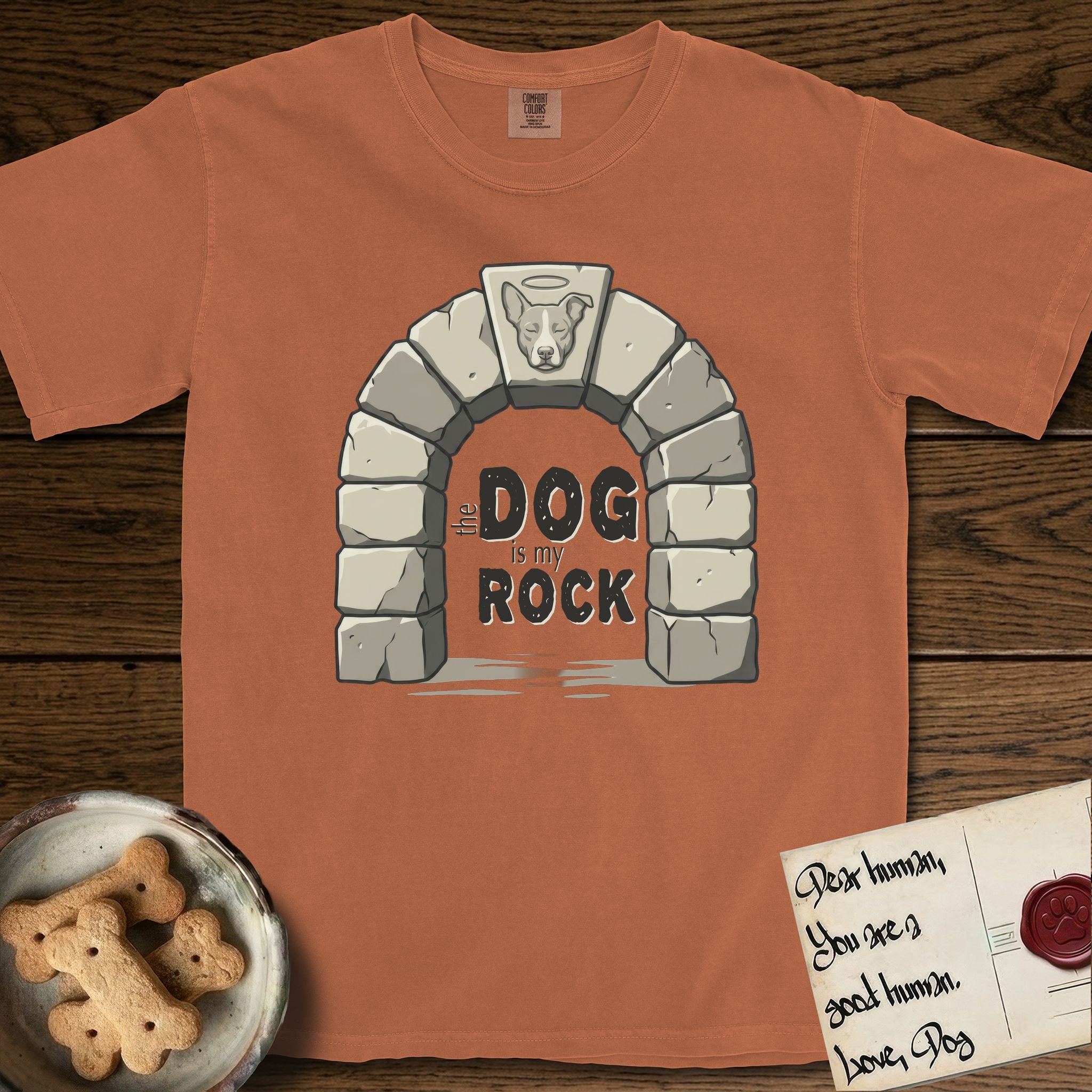 DIMR Lobo T-Shirt flat lay in Yam, featuring carved gray stone arch with Lobo's Cattle Dog face in shallow relief on the keystone and a halo above, with the words the Dog is my Rock.