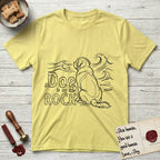 DIMR Saint Bernard T-Shirt flat lay in Cornsilk, featuring ink-line illustration of a Saint Bernard seen from behind, sitting at the water's edge and watching a stormy sea, with the words the Dog is my Rock.