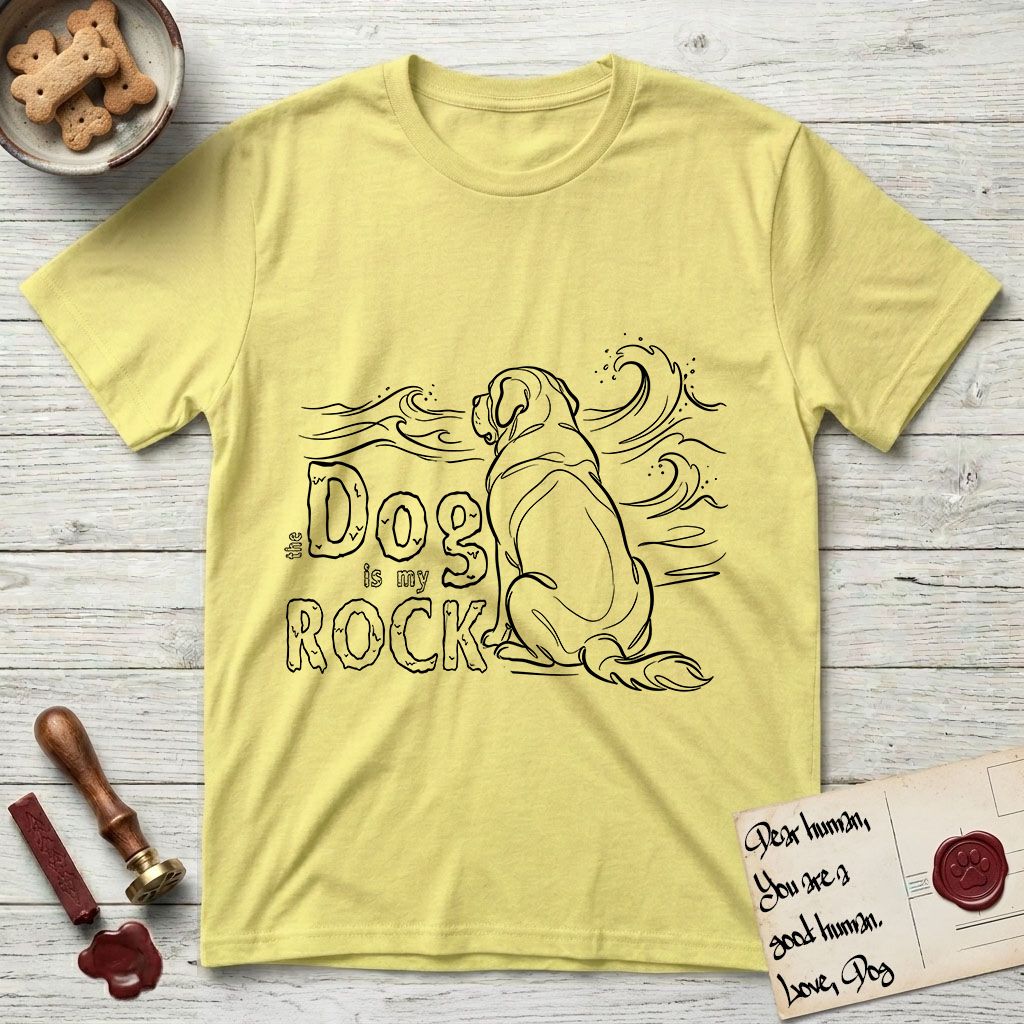 DIMR Saint Bernard T-Shirt flat lay in Cornsilk, featuring ink-line illustration of a Saint Bernard seen from behind, sitting at the water's edge and watching a stormy sea, with the words the Dog is my Rock.