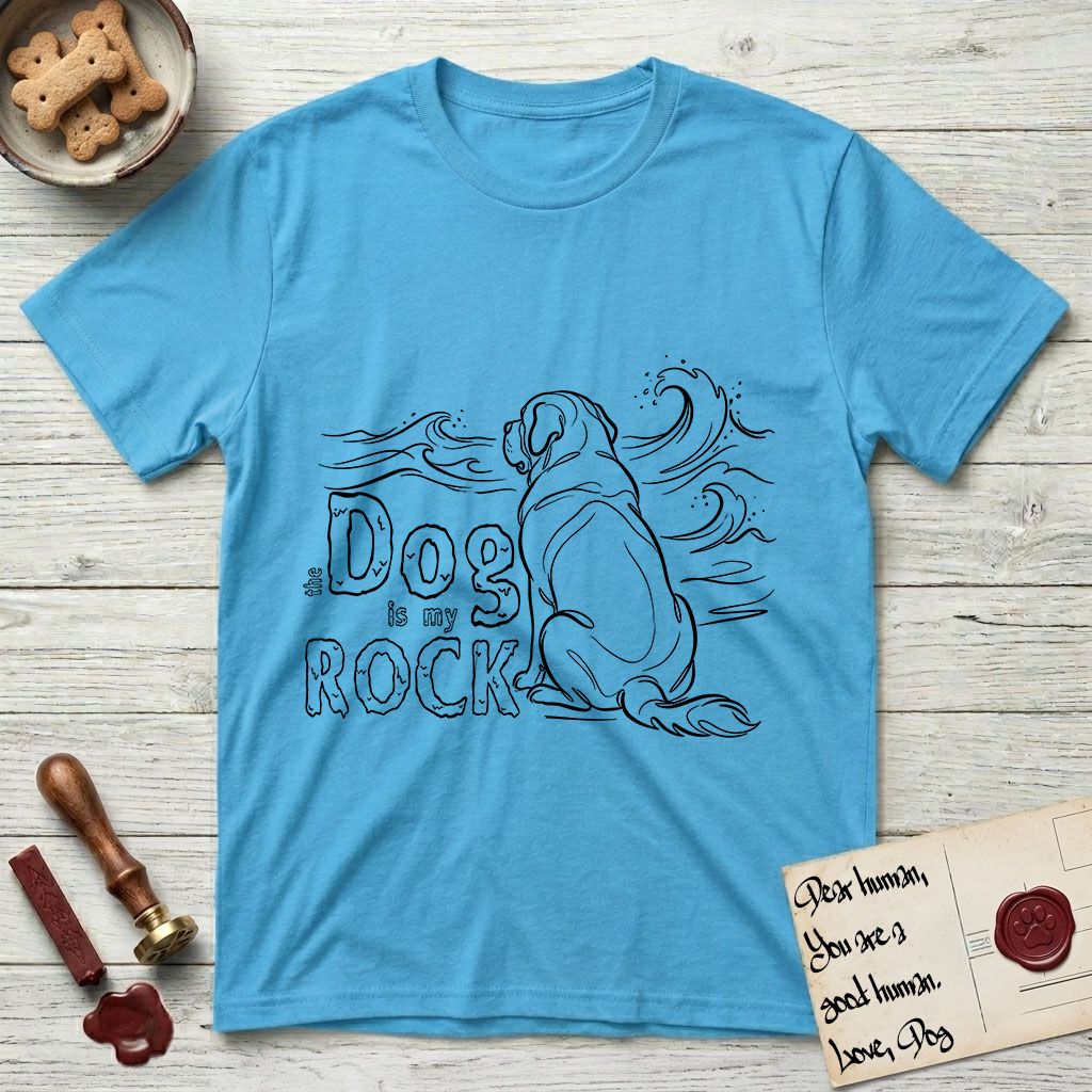 DIMR Saint Bernard T-Shirt flat lay in Sky, featuring ink-line illustration of a Saint Bernard seen from behind, sitting at the water's edge and watching a stormy sea, with the words the Dog is my Rock.