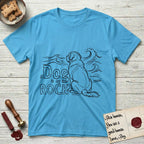 DIMR Saint Bernard T-Shirt flat lay in Sky, featuring ink-line illustration of a Saint Bernard seen from behind, sitting at the water's edge and watching a stormy sea, with the words the Dog is my Rock.