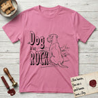 DIMR Schnauzer T-Shirt flat lay in Azalea, featuring ink-line illustration of a Schnauzer seen from behind at the water's edge, head turned toward a stormy sea, with the words the Dog is my Rock.