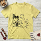 DIMR Schnauzer T-Shirt flat lay in Cornsilk, featuring ink-line illustration of a Schnauzer seen from behind at the water's edge, head turned toward a stormy sea, with the words the Dog is my Rock.