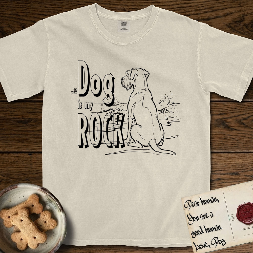 DIMR Schnauzer T-Shirt flat lay in Ivory, featuring ink-line illustration of a Schnauzer seen from behind at the water's edge, head turned toward a stormy sea, with the words the Dog is my Rock.