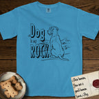 DIMR Schnauzer T-Shirt flat lay in Royal Caribe, featuring ink-line illustration of a Schnauzer seen from behind at the water's edge, head turned toward a stormy sea, with the words the Dog is my Rock.