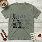 DIMR Schnauzer T-Shirt flat lay in Sage, featuring ink-line illustration of a Schnauzer seen from behind at the water's edge, head turned toward a stormy sea, with the words the Dog is my Rock.