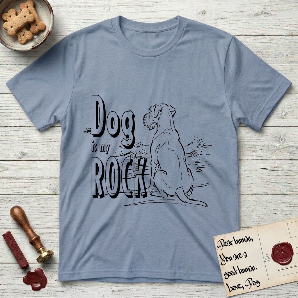 DIMR Schnauzer T-Shirt flat lay in Stone Blue, featuring ink-line illustration of a Schnauzer seen from behind at the water's edge, head turned toward a stormy sea, with the words the Dog is my Rock.