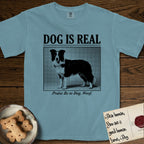 Dog is Real Border Collie T-Shirt flat lay in Ice Blue, featuring Black halftone newspaper photo of a black and white Border Collie standing in profile with head turned to the camera, under the headline DOG IS REAL, with the caption Praise Be to Dog. Woof..