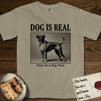 Dog is Real Boxer T-Shirt flat lay in Khaki, featuring Black halftone newspaper photo of a Boxer with a white chest standing in profile with head turned to the camera, under the headline DOG IS REAL, with the caption Praise Be to Dog. Woof..