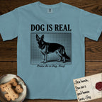Dog is Real German Shepherd T-Shirt flat lay in Ice Blue, featuring Black halftone newspaper photo of a black and tan German Shepherd with upright ears standing in profile with head turned to the camera, under the headline DOG IS REAL, with the caption Praise Be to Dog. Woof..