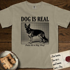 Dog is Real German Shepherd T-Shirt flat lay in Khaki, featuring Black halftone newspaper photo of a black and tan German Shepherd with upright ears standing in profile with head turned to the camera, under the headline DOG IS REAL, with the caption Praise Be to Dog. Woof..