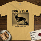 Dog is Real German Shepherd T-Shirt flat lay in Mustard, featuring Black halftone newspaper photo of a black and tan German Shepherd with upright ears standing in profile with head turned to the camera, under the headline DOG IS REAL, with the caption Praise Be to Dog. Woof..