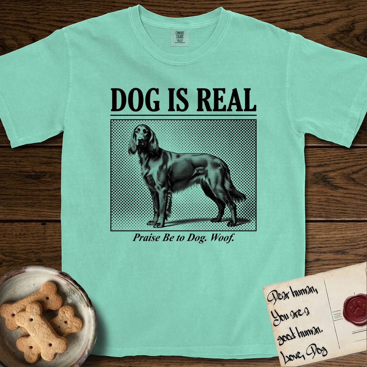 Dog is Real Irish Setter T-Shirt flat lay in Island Reef, featuring Black halftone newspaper photo of a feathered Irish Setter standing in profile with head turned to the camera, under the headline DOG IS REAL, with the caption Praise Be to Dog. Woof..