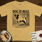 Dog is Real Jack Russell T-Shirt flat lay in Mustard, featuring Black halftone newspaper photo of a mostly white Jack Russell with dark ears and an upright tail standing in profile with head turned to the camera, under the headline DOG IS REAL, with the caption Praise Be to Dog. Woof..