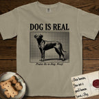 Dog is Real Rhodesian Ridgeback T-Shirt flat lay in Khaki, featuring Black halftone newspaper photo of a lean Rhodesian Ridgeback standing in profile with head turned to the camera, under the headline DOG IS REAL, with the caption Praise Be to Dog. Woof..