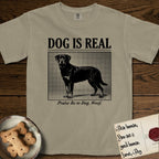 Dog is Real Rottweiler T-Shirt flat lay in Khaki, featuring Black halftone newspaper photo of a Rottweiler standing in profile with head turned to the camera, under the headline DOG IS REAL, with the caption Praise Be to Dog. Woof..