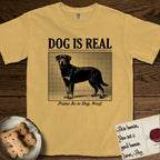 Dog is Real Rottweiler T-Shirt flat lay in Mustard, featuring Black halftone newspaper photo of a Rottweiler standing in profile with head turned to the camera, under the headline DOG IS REAL, with the caption Praise Be to Dog. Woof..