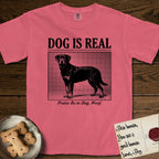 Dog is Real Rottweiler T-Shirt flat lay in Watermelon, featuring Black halftone newspaper photo of a Rottweiler standing in profile with head turned to the camera, under the headline DOG IS REAL, with the caption Praise Be to Dog. Woof..