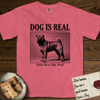 Dog is Real Shar-Pei T-Shirt flat lay in Watermelon, featuring Black halftone newspaper photo of a wrinkled Shar-Pei with a curled tail standing in profile with head turned to the camera, under the headline DOG IS REAL, with the caption Praise Be to Dog. Woof..