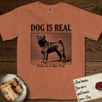 Dog is Real Shar-Pei T-Shirt flat lay in Yam, featuring Black halftone newspaper photo of a wrinkled Shar-Pei with a curled tail standing in profile with head turned to the camera, under the headline DOG IS REAL, with the caption Praise Be to Dog. Woof..